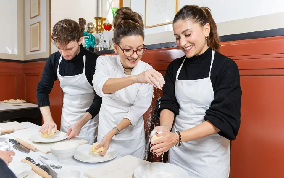 Ospiti che impastano la pasta con un istruttore