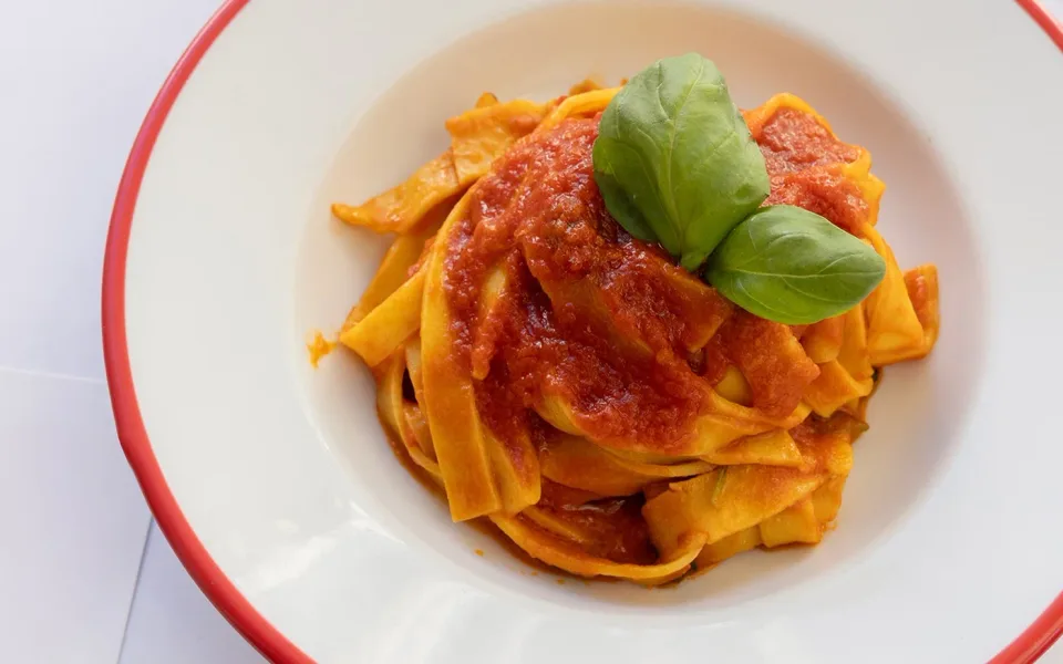Pasta fresca servita con salsa di pomodoro e basilico
