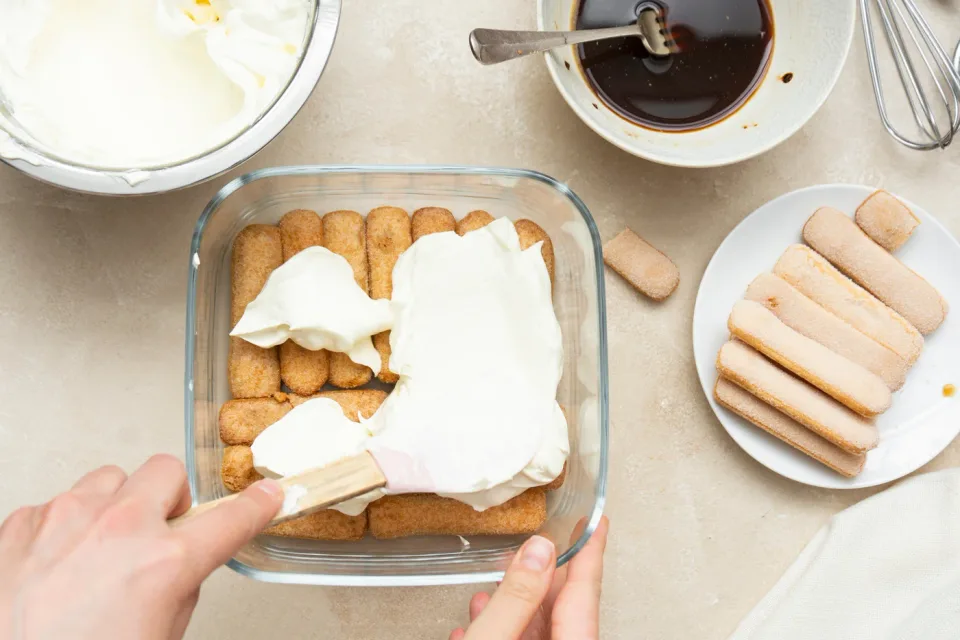 Stratificando crema e biscotti mentre si prepara il tiramisù